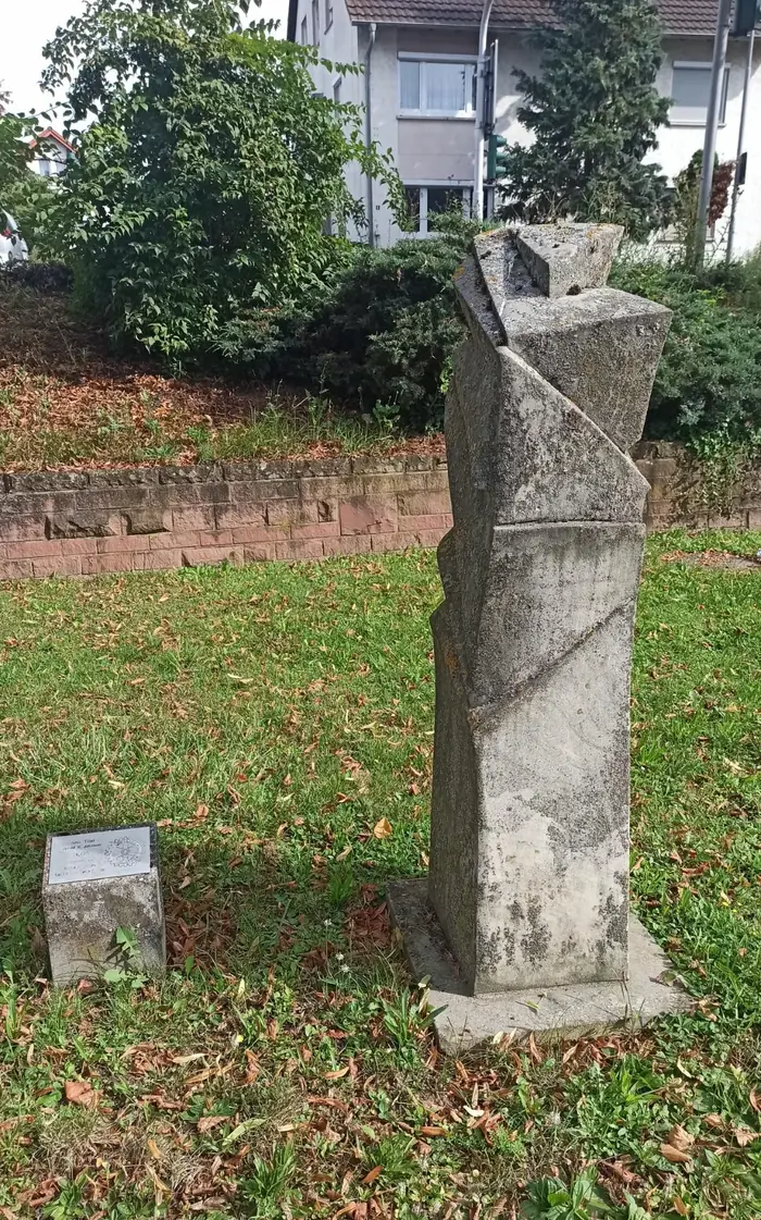 Hohe, schlanke Steinskulptur von Johnson auf einer Wiese im Stadtgraben von Tauberbischofsheim